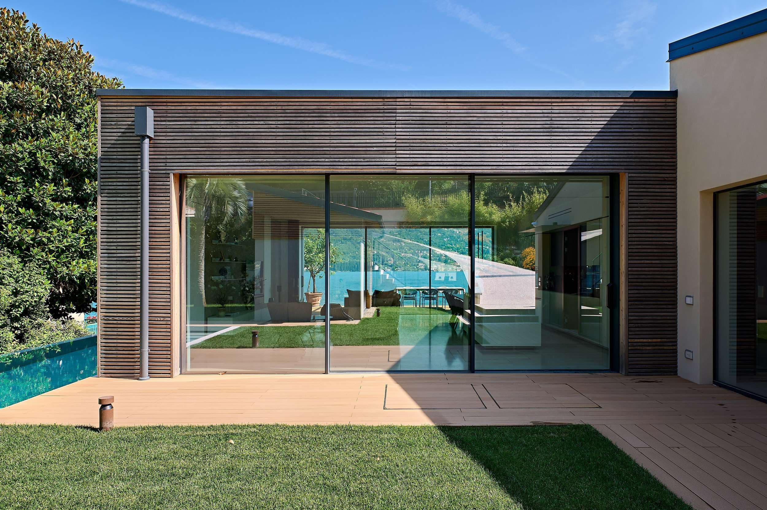 Villa sul Lago di Garda: la parete scorrevole Hi-Finity aperta sul prato e sulla piscina, con il lago sullo sfondo
